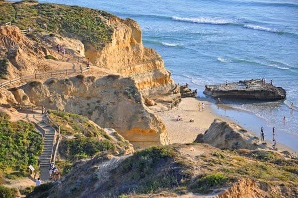 A cliff with stairs leading down to the beach.