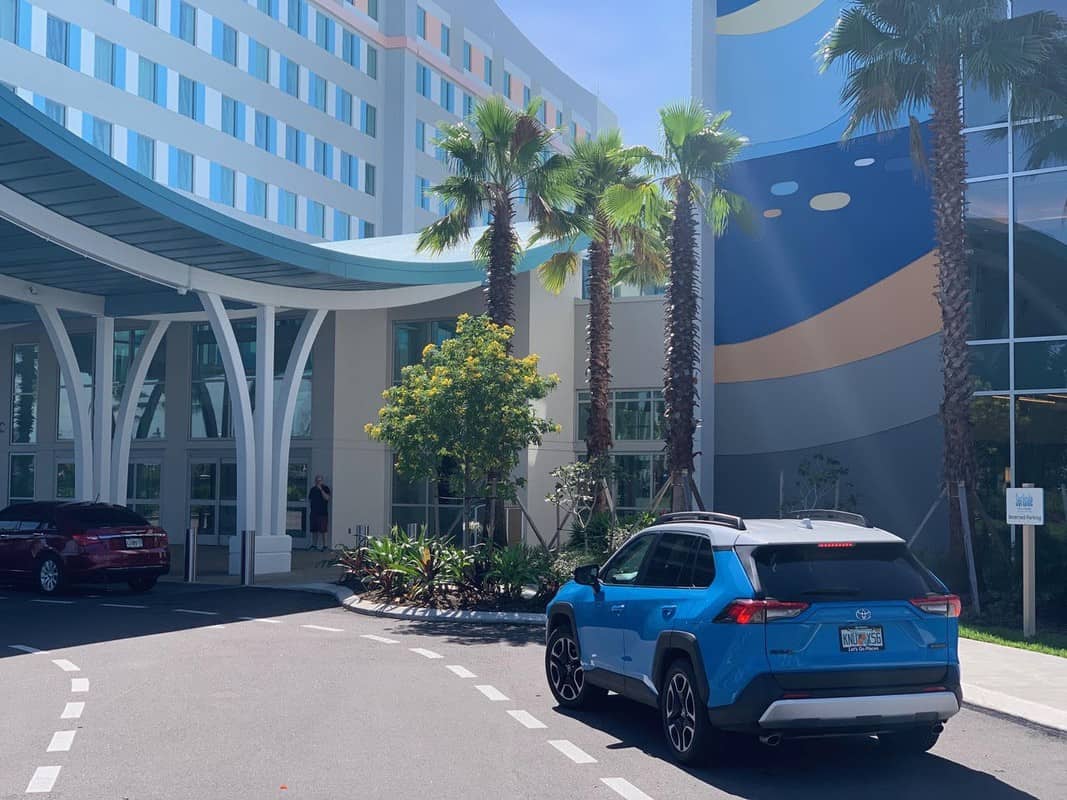 A blue suv parked in front of a building with palm trees.