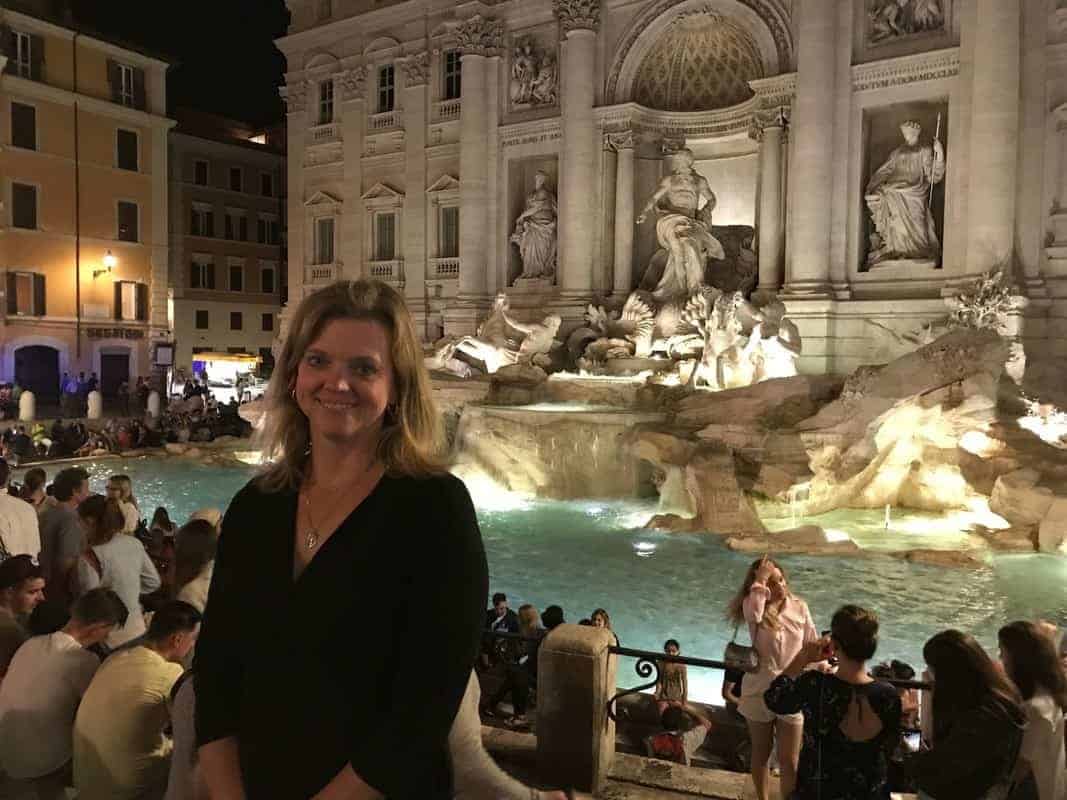 A woman poses with the Southwest Priority Card in front of the Trevi Fountain at night.