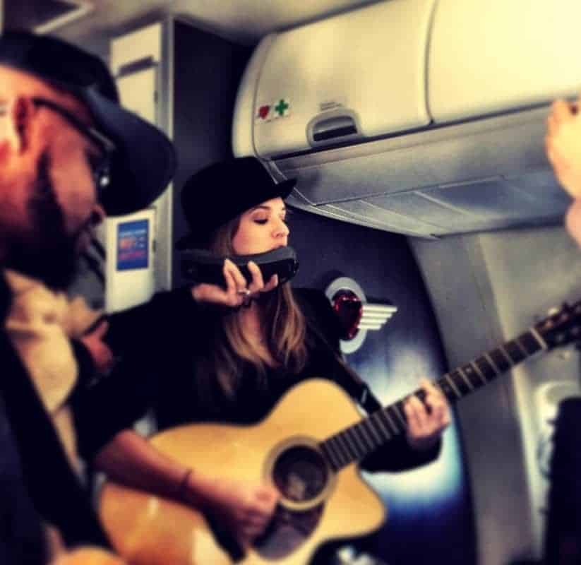 A group of people playing guitar on a Southwest airplane.