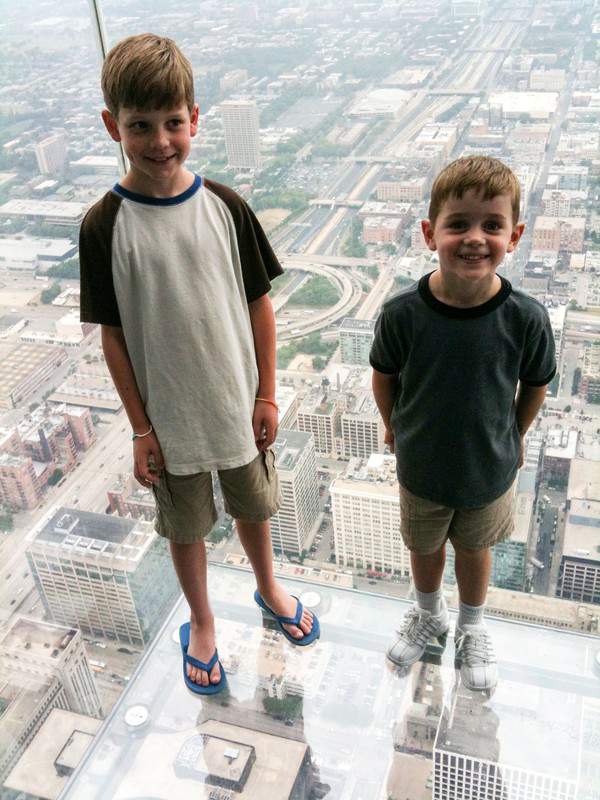 Two boys on Willis Tower Skydeck with view of city below