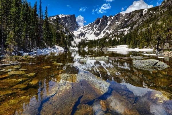 Rocky Mountain National Park: A lake surrounded by snowy mountains and trees.