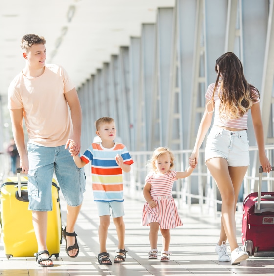 A family with luggage walking through an airport.