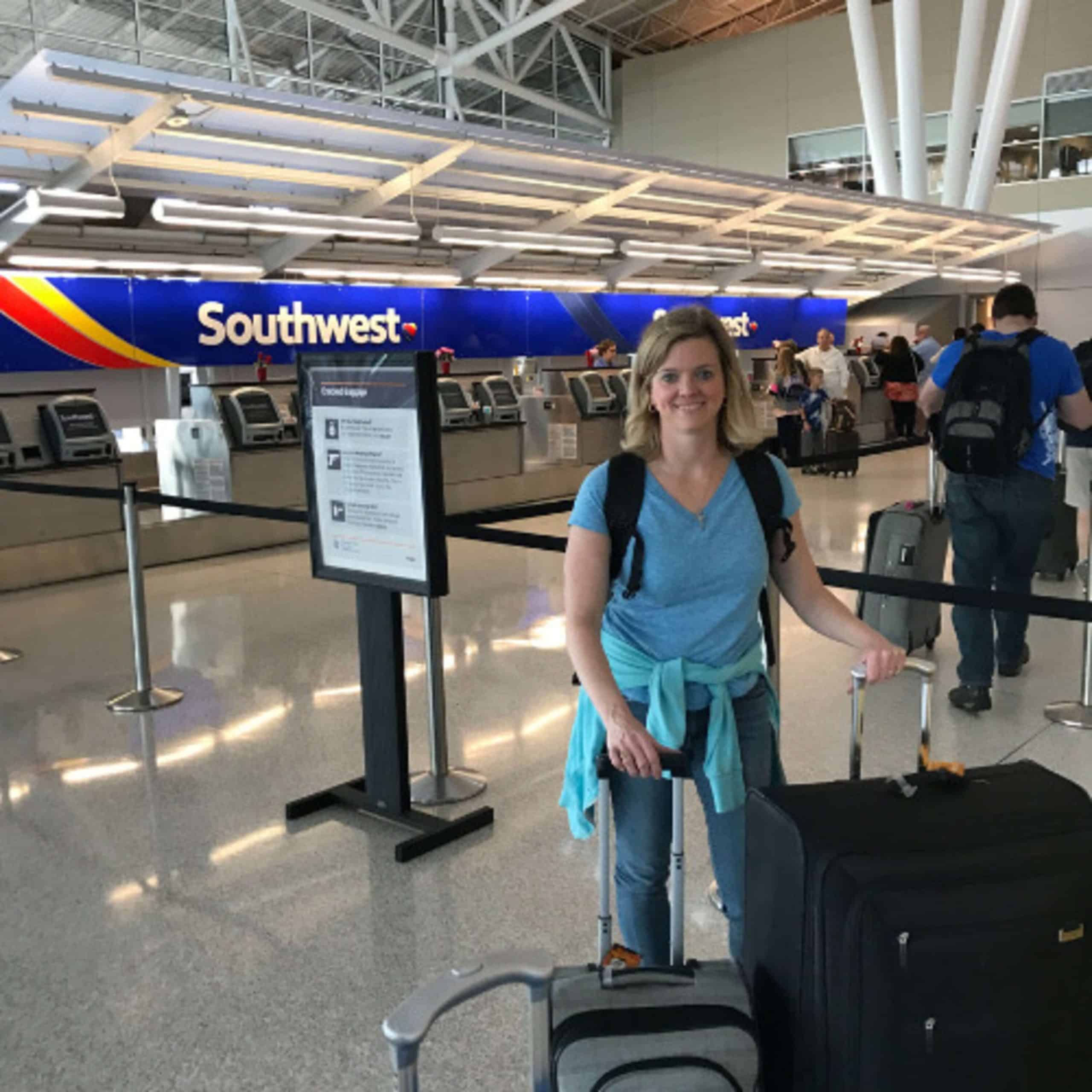 A woman standing with her luggage at an airport.