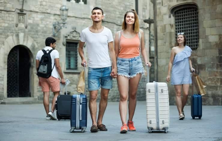 A group of people with luggage walking down a street.