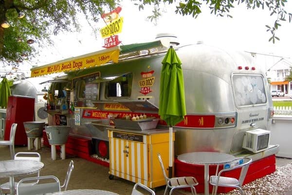 An airstream food truck with tables and chairs outside.