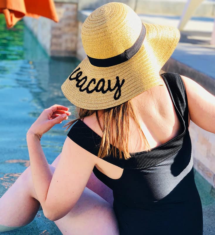 woman wearing floppy hat that says "vacay" at cruise ship pool