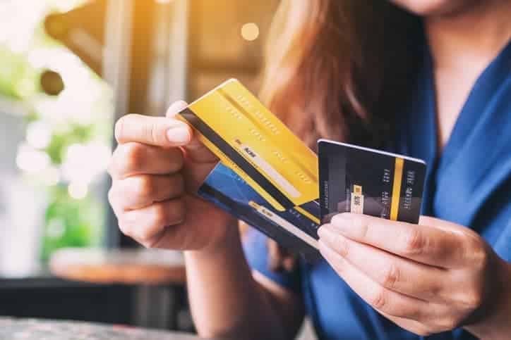 A woman holding two credit cards at a table.